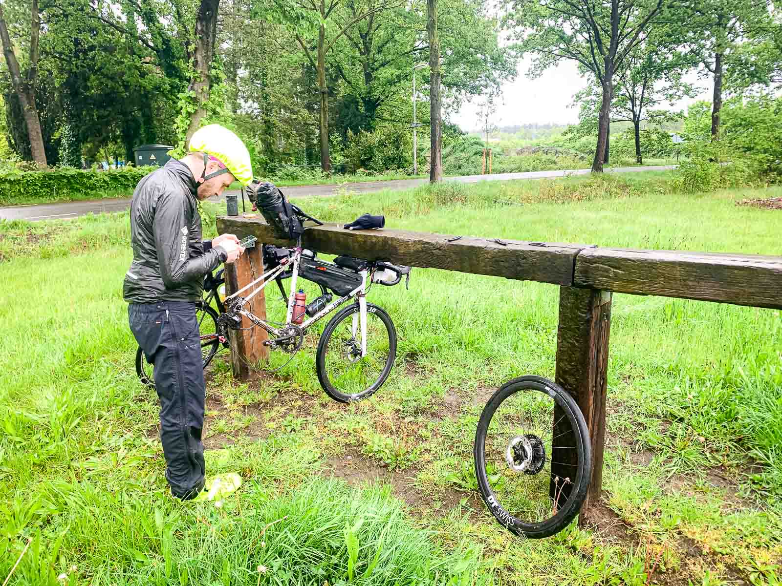 Una bicicletta con una gomma sgonfia è appesa a un parapetto di legno.