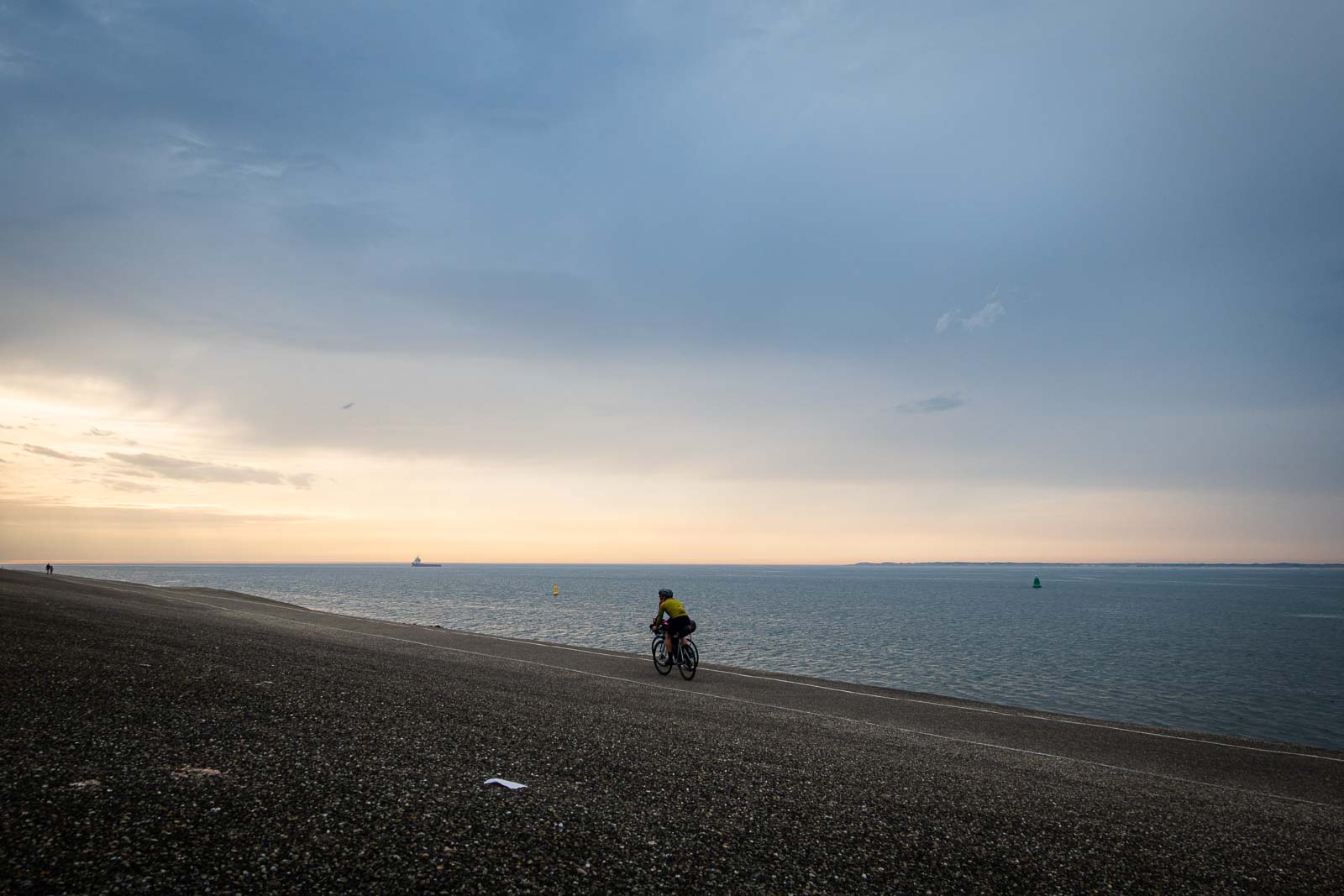 Due partecipanti alla Race around the Netherlands pedalano verso il sole della sera.