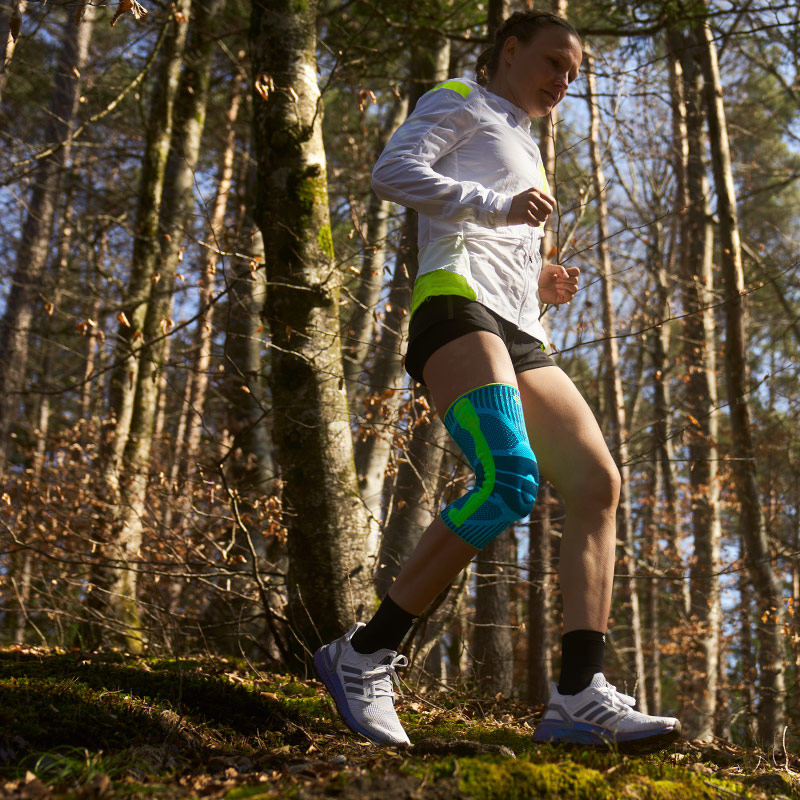 Anna Hahner corre lungo il sentiero forestale con una fascia al ginocchio