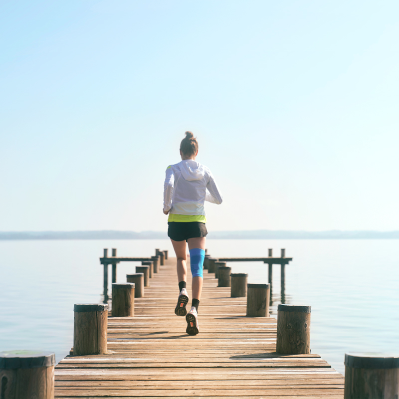 Anna Hahner corre con il suo supporto per il ginocchio di compressione sportiva tramite un molo verso il lago