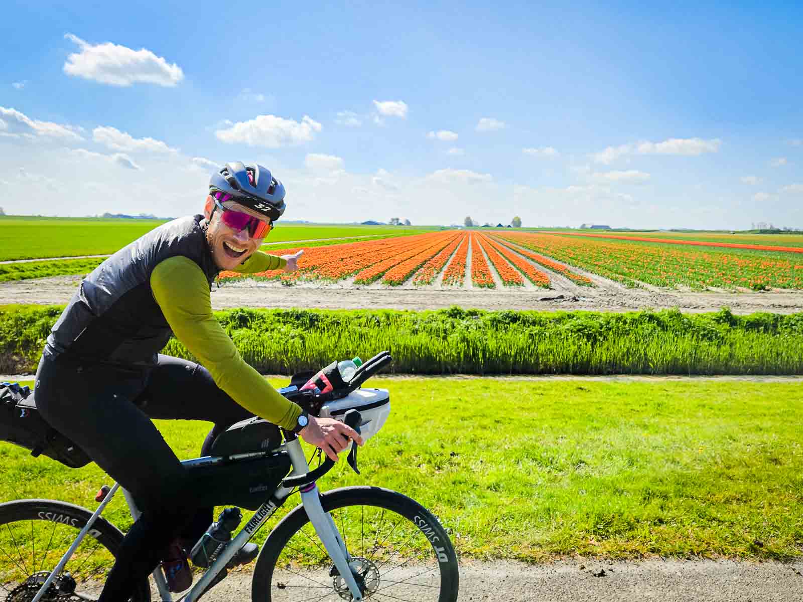 Un partecipante alla Race arouund the Netherlands si gode la vista dei fiori colorati e li indica