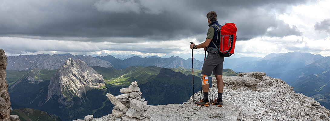 Alpinista sulla vetta di una montagna che indossa una ginocchiera da esterno