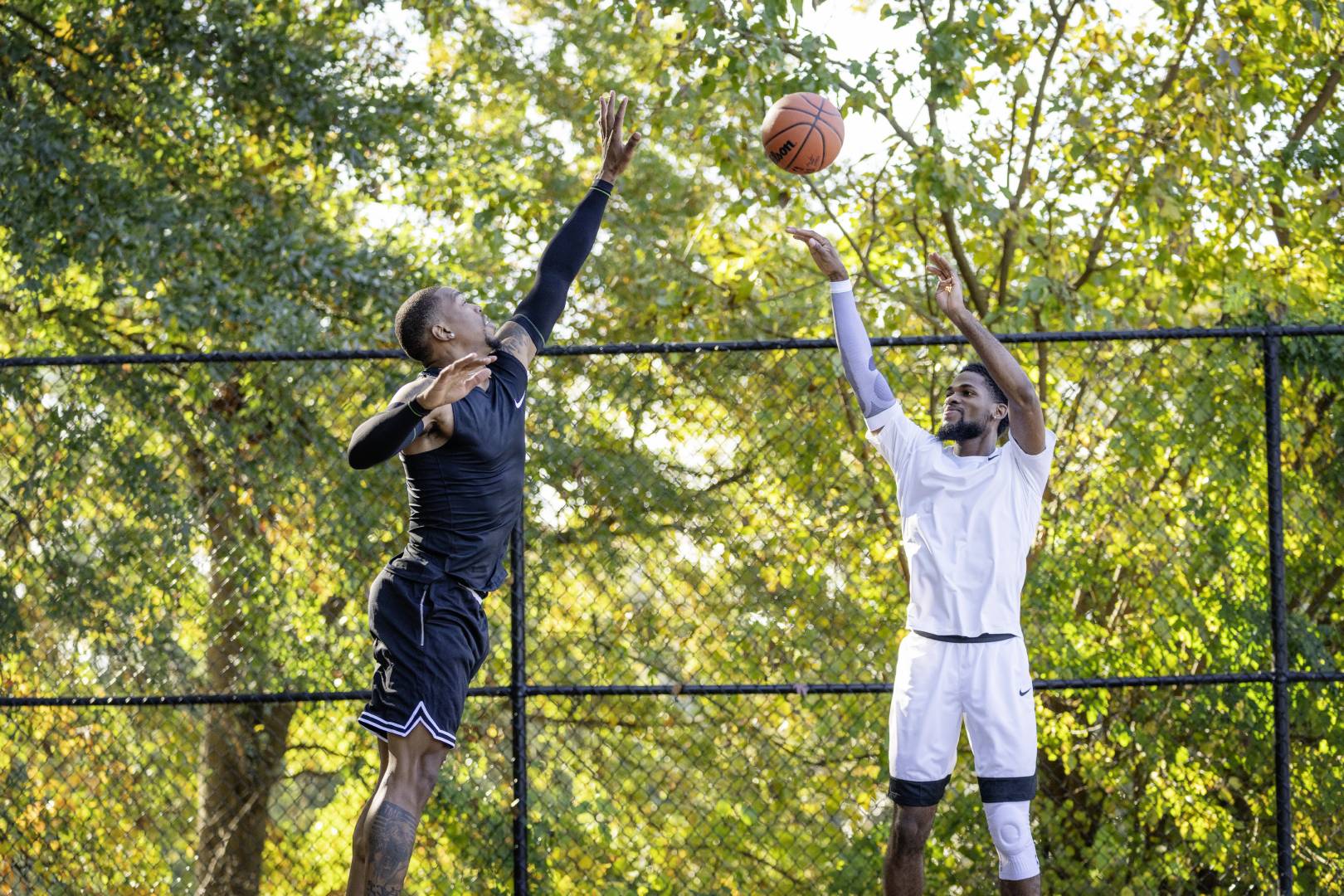 I giocatori di basket in abbigliamento da gioco nero cerca di bloccare il suo avversario in abiti bianchi in alto sopra il suolo