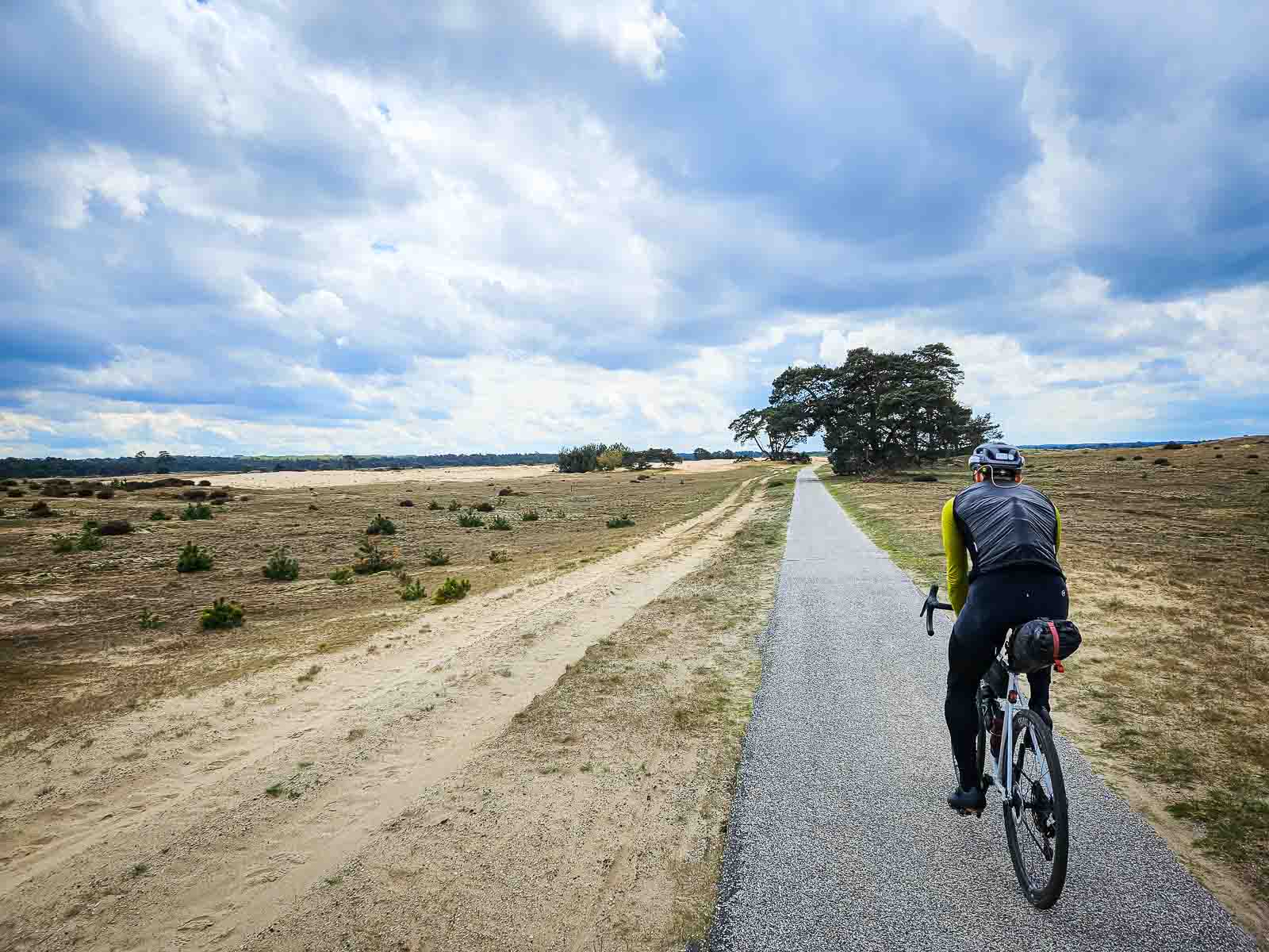 Un ciclista percorre un lungo rettilineo attraverso un bellissimo paesaggio di brughiera.