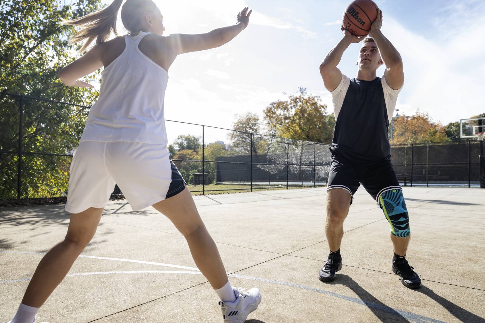 I giocatori di basket con il ginocchio iniziano con uno streetball mentre il suo avversario cerca di bloccarlo