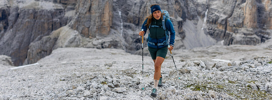 Donna che fa escursioni su un terreno roccioso nelle Alpi.