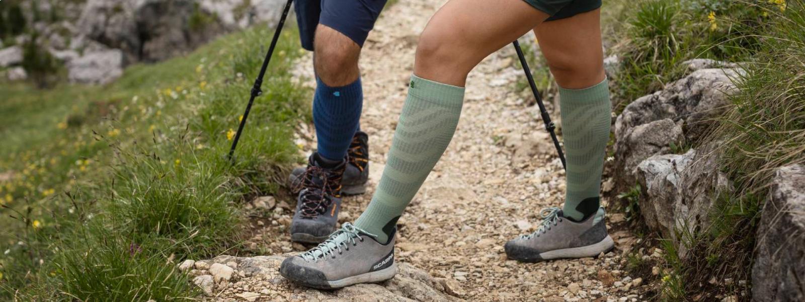 Estratto di quattro gambe con calzini da trekking merino misericordiosi su un sentiero escursionistico